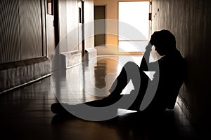 Silhouette of depressed man sitting on walkway of residence building. Sad man, Cry, drama, lonely and unhappy concept