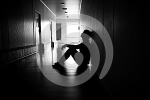 Silhouette of depressed man sitting on walkway of residence building. Sad man, Cry, drama, lonely and unhappy concept