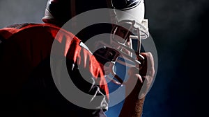 Silhouette of determined American football player in bright stadium light preparing for a night game. Concept of