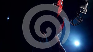 Silhouette of determined American football player in bright stadium light preparing for a night game. Sportsman in