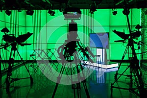 Silhouette of a digital video camera in front of a green screen.