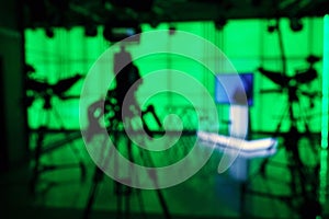 Silhouette of a digital video camera in front of a green screen.