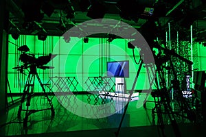 Silhouette of a digital video camera in front of a green screen.