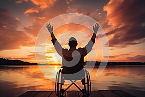 Silhouette disabled man, handicapped young man in wheelchair raised hands in sunset