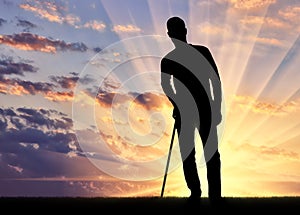 Silhouette of a disabled man supports himself with a crutch