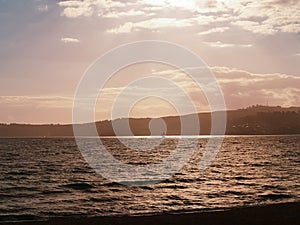 Silhouette distant hills and yacht sailing in under red sky at sunset