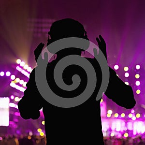 Silhouette of DJ wearing headphones and performing at a night club