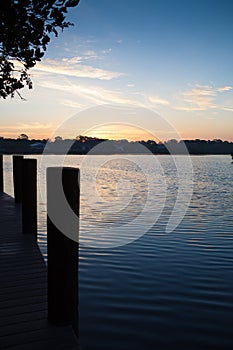 Silhouette of dock pilings over water and sunrise