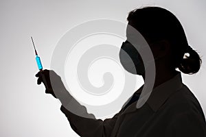 Silhouette of a doctor with syringe filled with blue liquid. Vaccination concept.