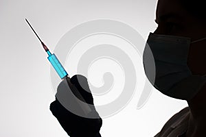 Silhouette of a doctor with syringe filled with blue liquid. Vaccination concept.