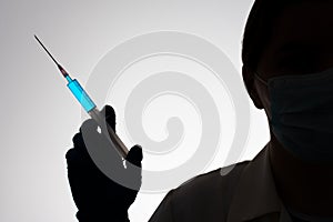 Silhouette of a doctor with syringe filled with blue liquid. Vaccination concept.