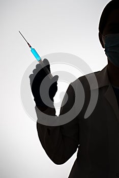 Silhouette of a doctor with syringe filled with blue liquid. Vaccination concept.