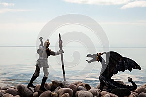 Silhouette of dragon and knight on the pebbled shore