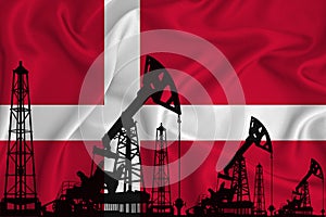 Silhouette of drilling rigs and oil derricks on the background of the flag of Denmark. Oil and gas industry. The concept of oil