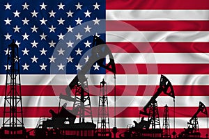 Silhouette of drilling rigs and oil derricks on the background of the flag of US. Oil and gas industry. The concept of oil fields