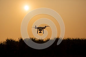 Silhouette drone against the background of the sunset. Flying drones in the evening sky.