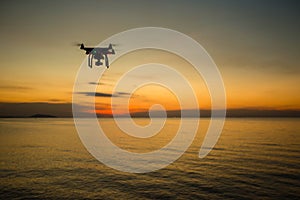 Silhouette drone against the background of the sunset. Flying drones in the evening sky. UAV Drone with digital camera.