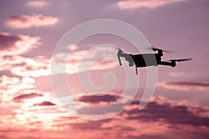 Silhouette of drone hovering in a colorful sunset. Toned image.