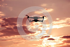 Silhouette of drone hovering in a colorful sunset. Toned image.