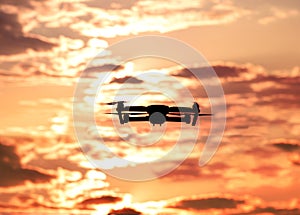 Silhouette of drone hovering in a colorful sunset. Toned image.