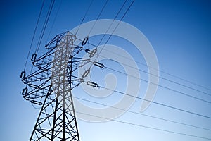 Silhouette of electrical pylon over light blue sky