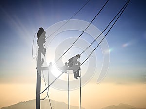 Silhouette electrical workers are installing high voltage system