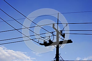 Silhouette electricity post with wired and blue sky background