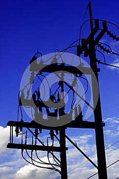 Silhouette electricity post with wired and blue sky background