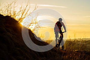 Silhouette of Enduro Cyclist Riding the Mountain Bike on the Rocky Trail at Sunset. Active Lifestyle Concept. Space for Text.