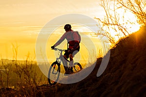 Silhouette of Enduro Cyclist Riding the Mountain Bike on the Rocky Trail at Sunset. Active Lifestyle Concept. Space for Text.