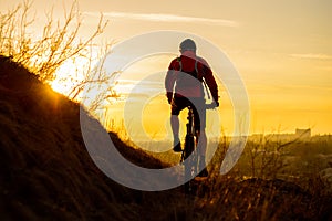 Silhouette of Enduro Cyclist Riding the Mountain Bike on the Rocky Trail at Sunset. Active Lifestyle Concept. Space for Text.