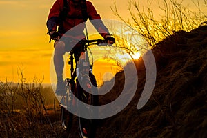 Silhouette of Enduro Cyclist Riding the Mountain Bike on the Rocky Trail at Sunset. Active Lifestyle Concept. Space for Text.