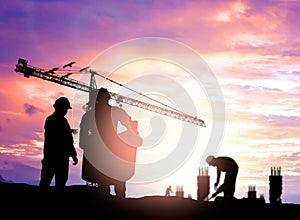 Silhouette engineer looking construction worker under tower cran in a building site over Blurred construction worker on construct