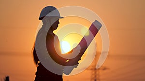 Silhouette of an engineer looks at the project of construction of a high-voltage power plant. The engineer is reading