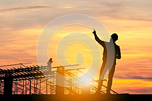 Silhouette of Engineer man with clipping path and worker on building site, construction site at sunset in evening time