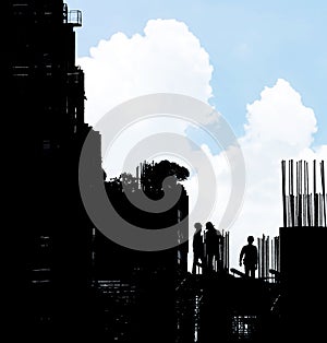 Silhouette of engineer standing orders for construction crews to work safely on high ground over blurred building.