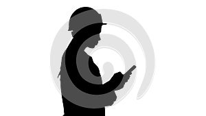 Silhouette Engineer using mobile phone texting while walking.