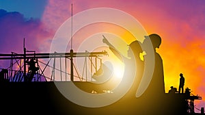 Silhouette of Engineer and worker building construction site background at sunset in evening time