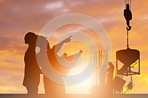 Silhouette of Engineer and worker building construction site background at sunset in evening time
