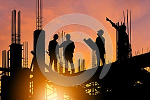 Silhouette of Engineer and worker on building site, construction site at sunset in evening time