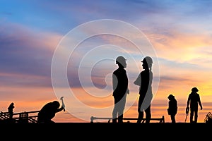 Silhouette of Engineer and worker on building site, construction site at sunset in evening time