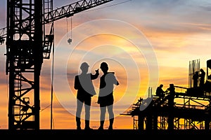 Silhouette of Engineer and worker on building site, construction site at sunset in evening time