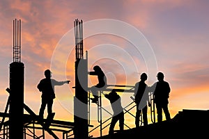 Silhouette of Engineer and worker on building site, construction site at sunset in evening time