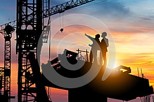 Silhouette of Engineer and worker checking project at building site background, construction site at sunset in evening time