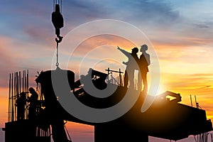 Silhouette of Engineer and worker checking project at building site background, construction site at sunset in evening time