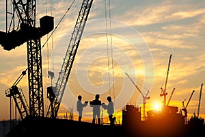 Silhouette of Engineer and worker team on building site, construction site at sunset in evening time