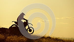 Silhouette of extreme motocross biker riding motor bike on sunrise background