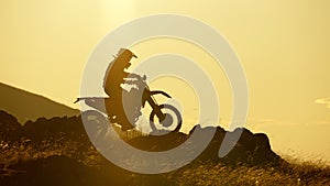 Silhouette of Extreme Motocross Biker riding motor bike on yellow sky background