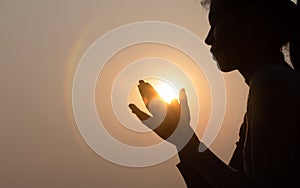 Silhouette of faithful woman praying at sunset as concept for religion, faith, prayer and spirituality