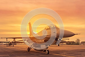 Silhouette falcon fighter jet military aircraft parked on runway in sunset